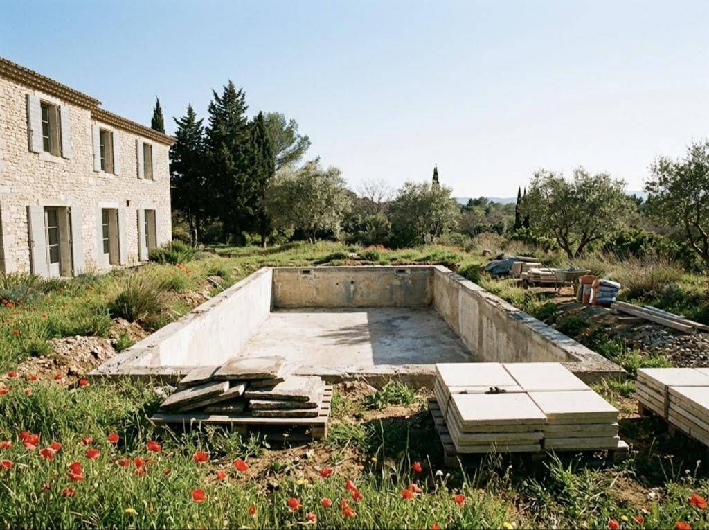 Bassin ancien en cours de rénovation, margelles déposées, coquelicots au bord